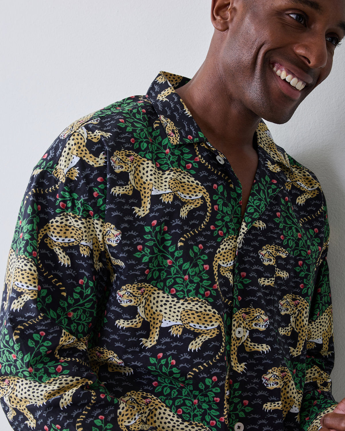 Close-up of a person wearing a dark button-front shirt with a yellow spotted cat and green foliage pattern.