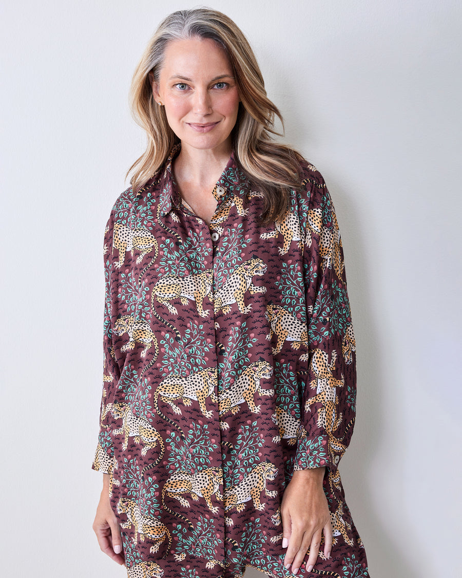 Front view of a raisin pajama set with leopard-and-leaf print, a collared button-front top, long sleeves, and wide-leg pants.
