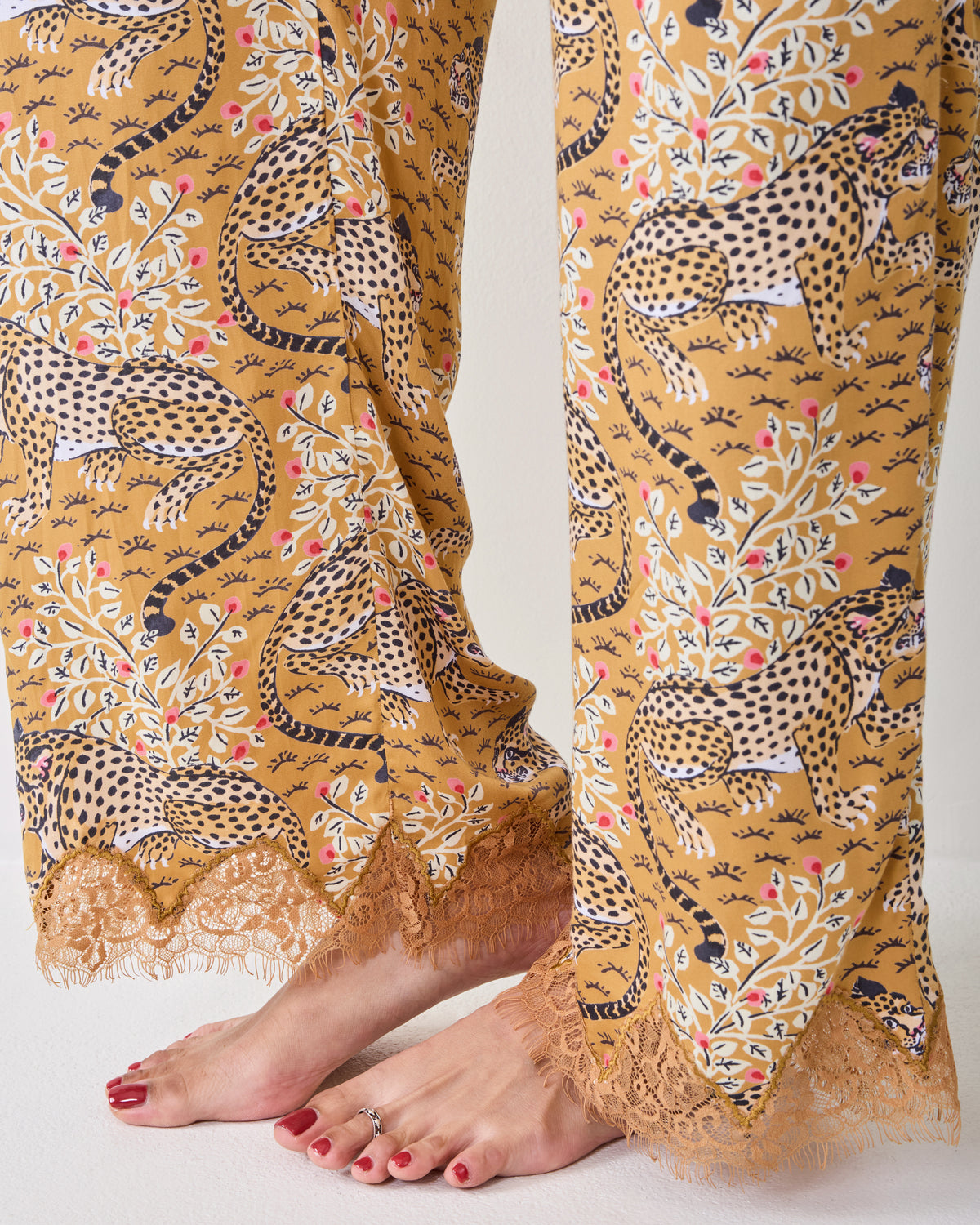 Close-up of the Tobacco Bagheera wide-leg pants showing the leopard print and lace-trimmed hems.