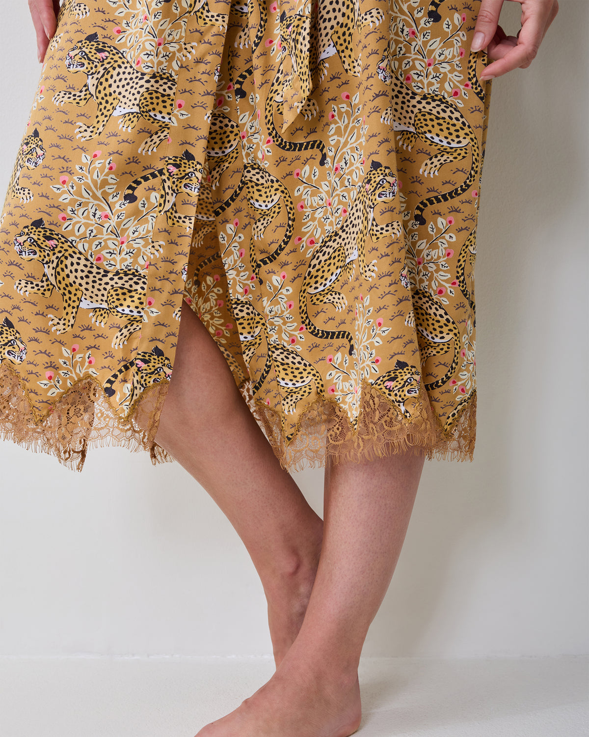 Close-up of the Bagheera tobacco lace robe hem showing the leopard-and-floral print and lace trim.