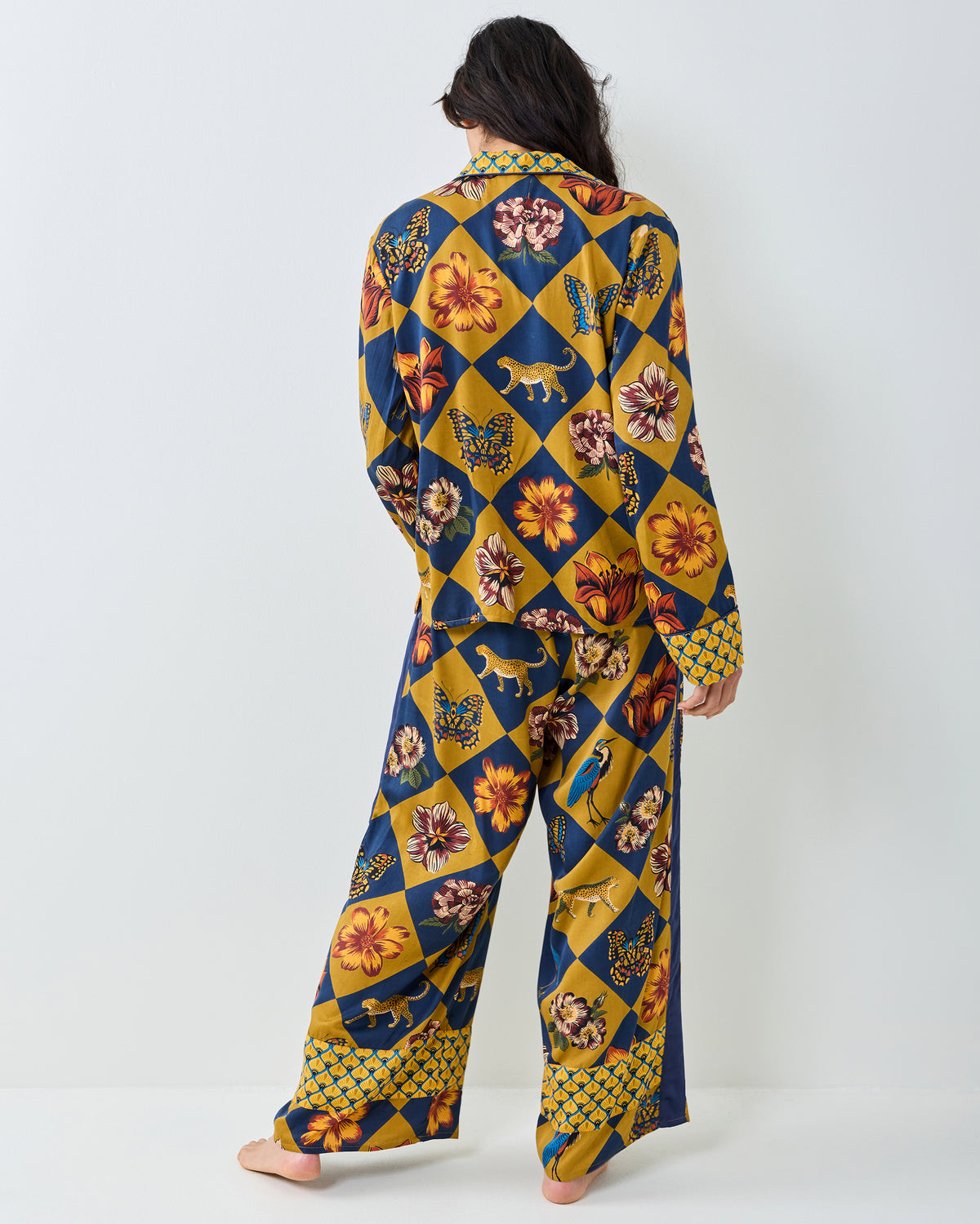 Back view of the Botanical Checkerboard Rittenhouse pajama set with a long-sleeve top and wide-leg pants featuring floral, butterfly, and leopard motifs.