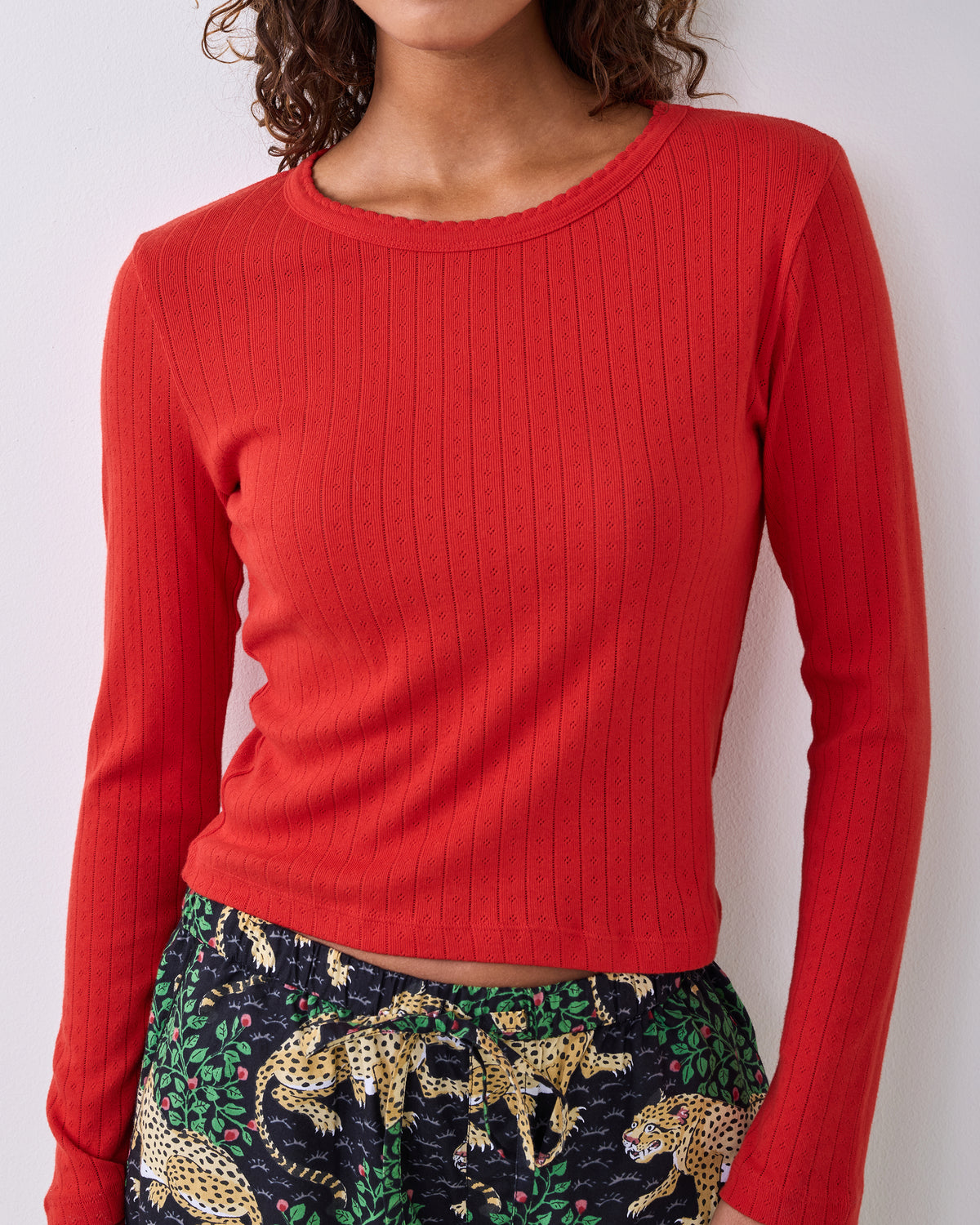 Candy crimson long-sleeve pointelle knit top with a scalloped neckline, shown on a model