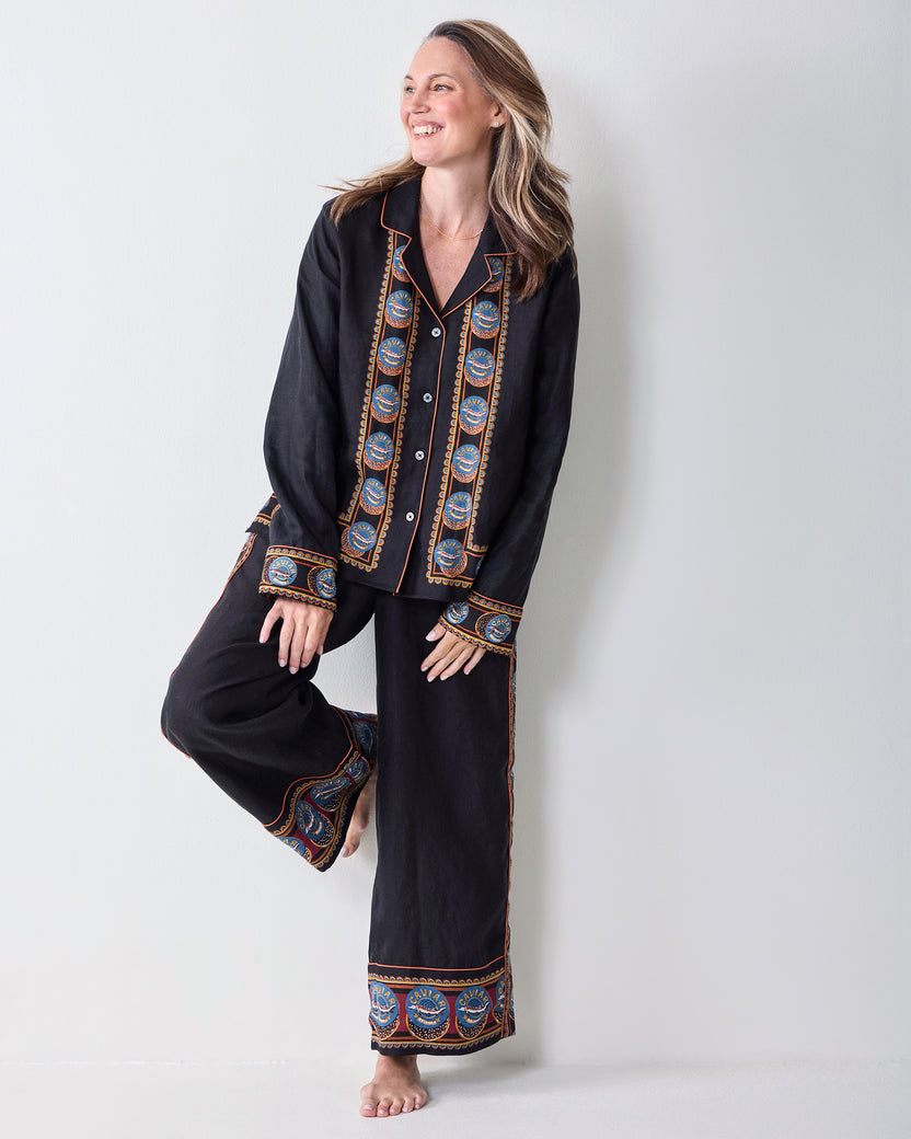 Full-length view of a black tunic top and wide-leg pants with blue, orange, and tan decorative border panels.
