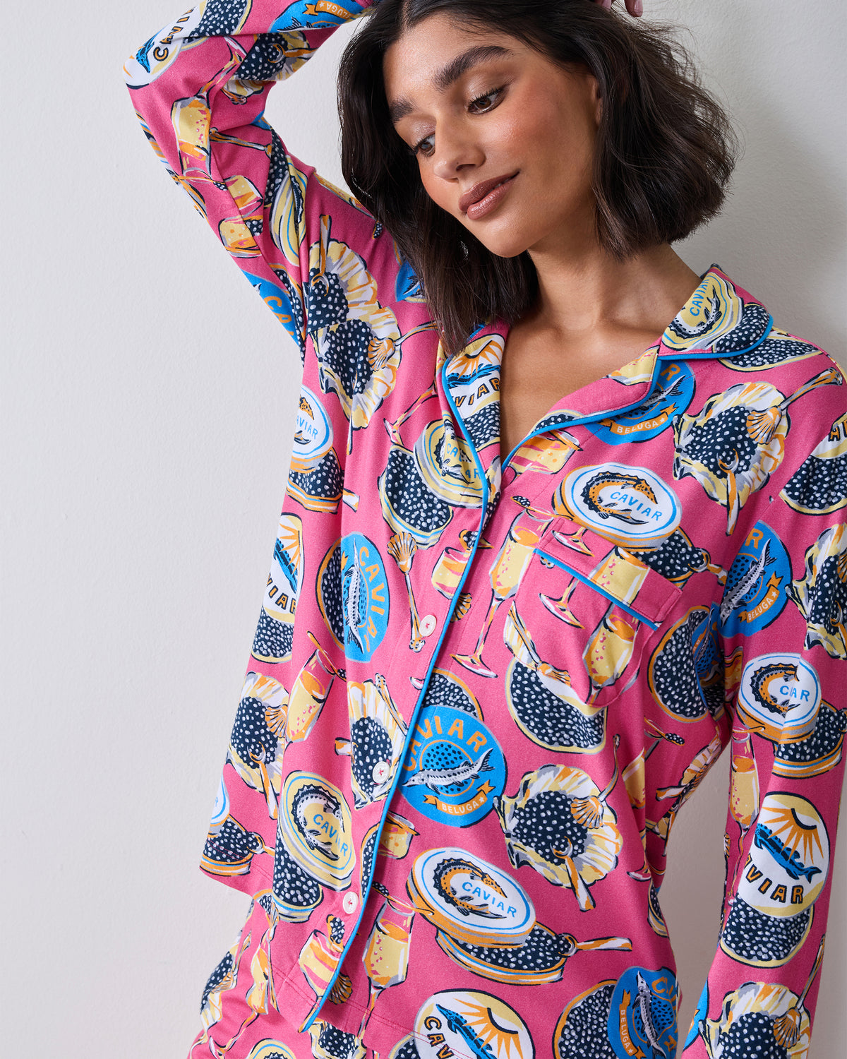Close view of the hot pink Champagne & Caviar pajama top with contrasting piping, collar, chest pocket, and printed caviar and champagne motifs.