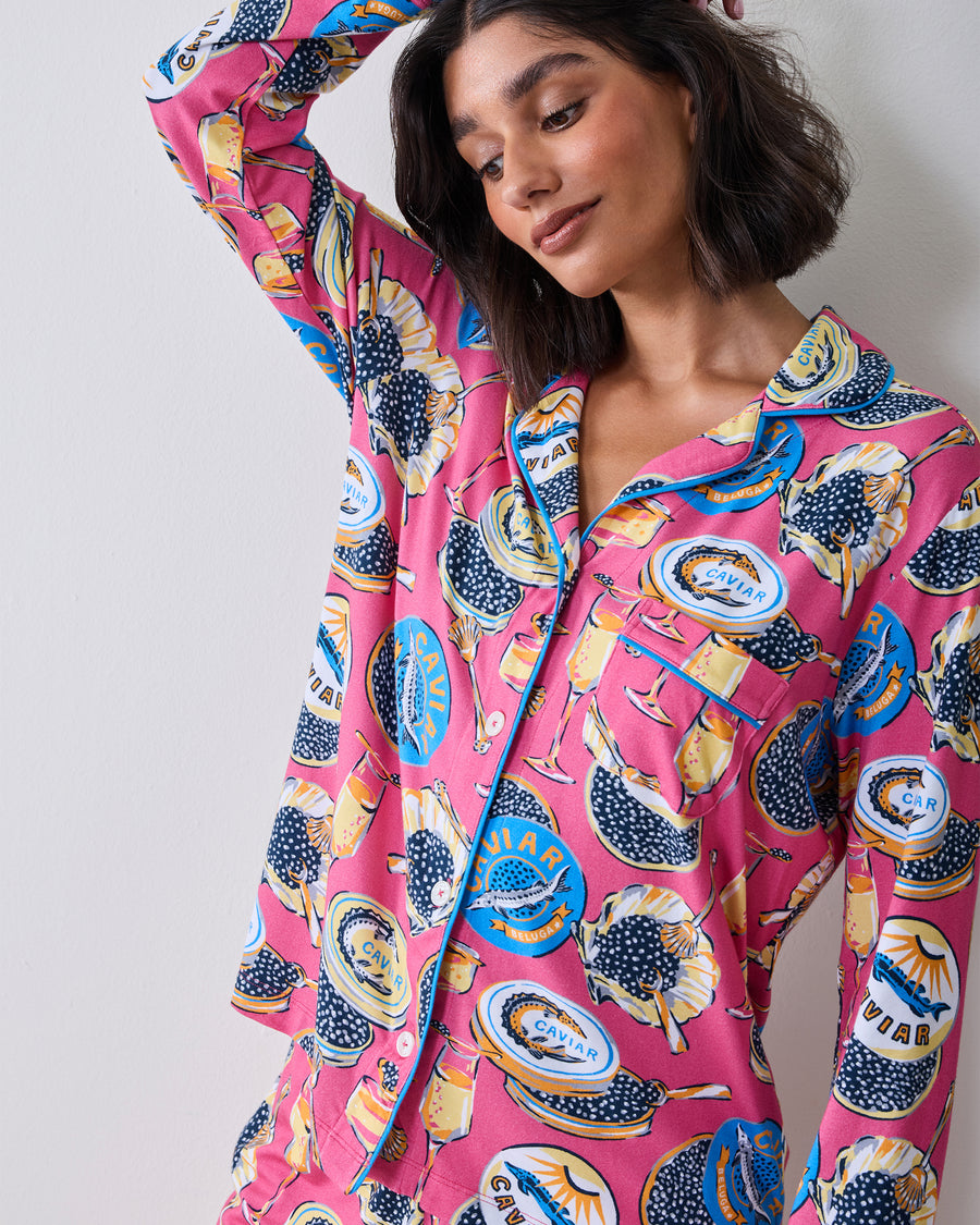 Close view of the hot pink Champagne & Caviar pajama top with contrasting piping, collar, chest pocket, and printed caviar and champagne motifs.