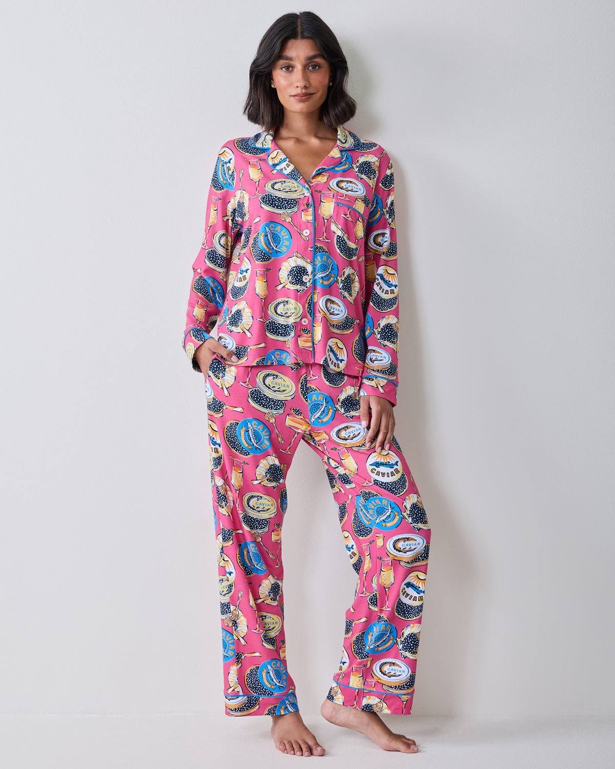 Full-length front view of a model wearing the hot pink Champagne & Caviar long pajama set with a button-front top and matching pants.
