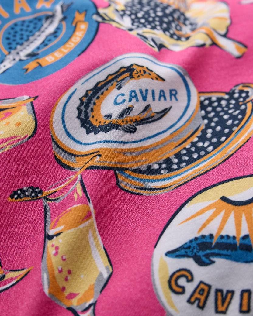 Close-up of the Champagne & Caviar print showing a caviar tin, champagne glass, and fish illustrations on hot pink fabric.