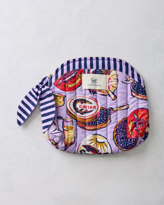 Lavender quilted Champagne & Caviar makeup bag with rounded top, striped trim, zipper closure, and side tie.
