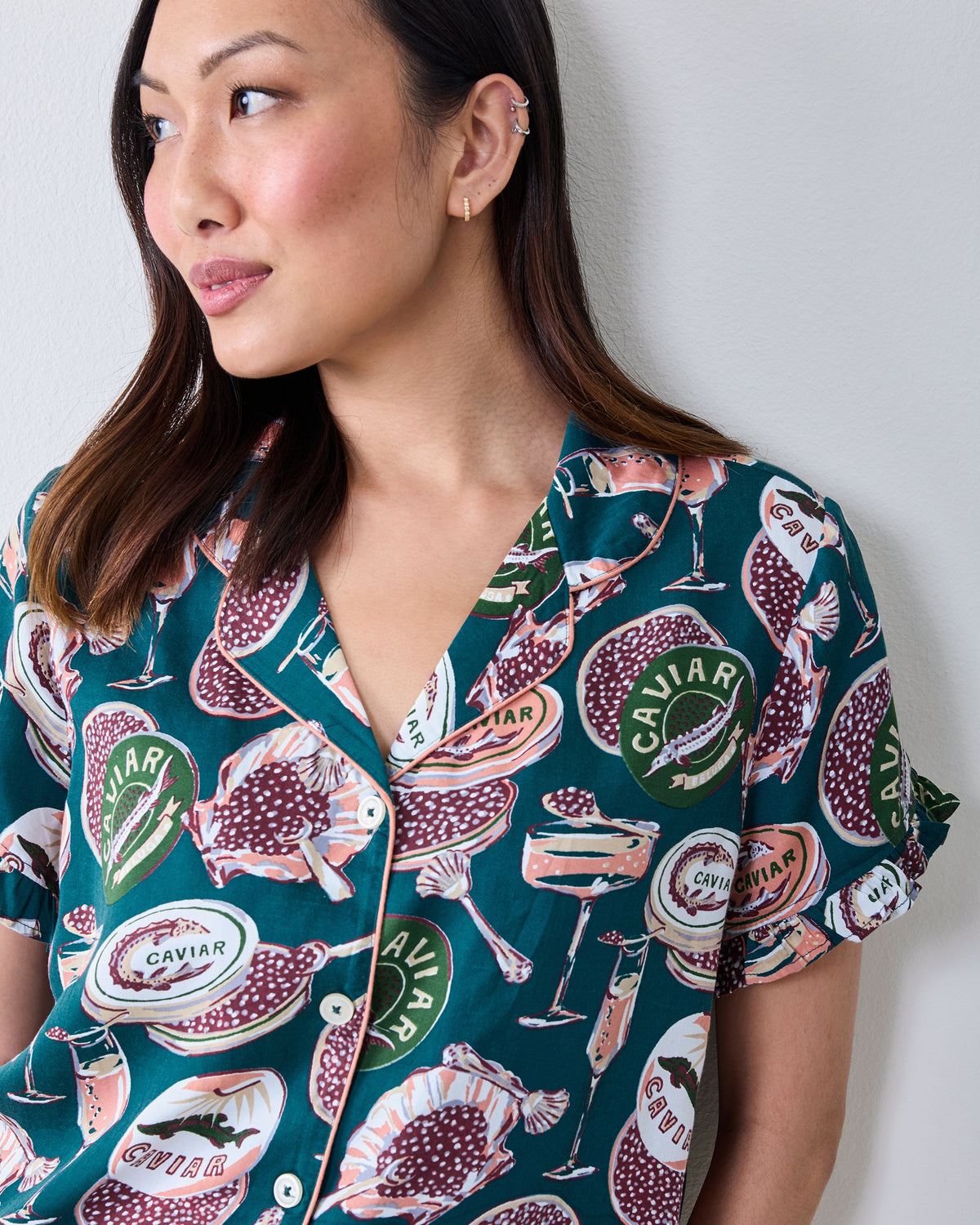 Close view of the short-sleeve satin pajama top with ruffled sleeves and a caviar-themed print.