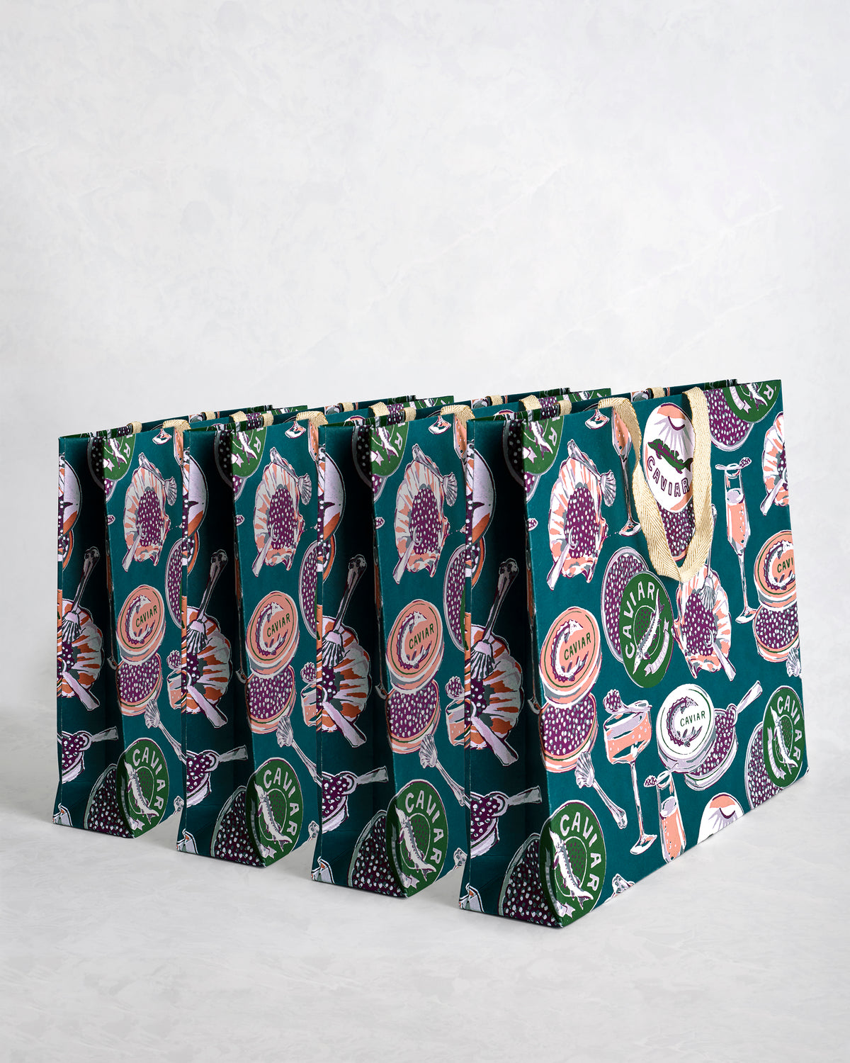 Set of four teal paper gift bags with Champagne & Caviar print and sparkly handles.