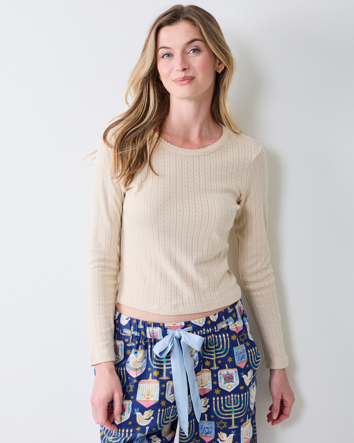 Front view of the cool ecru long-sleeve pointelle top with scalloped neckline, paired with patterned pajama pants.