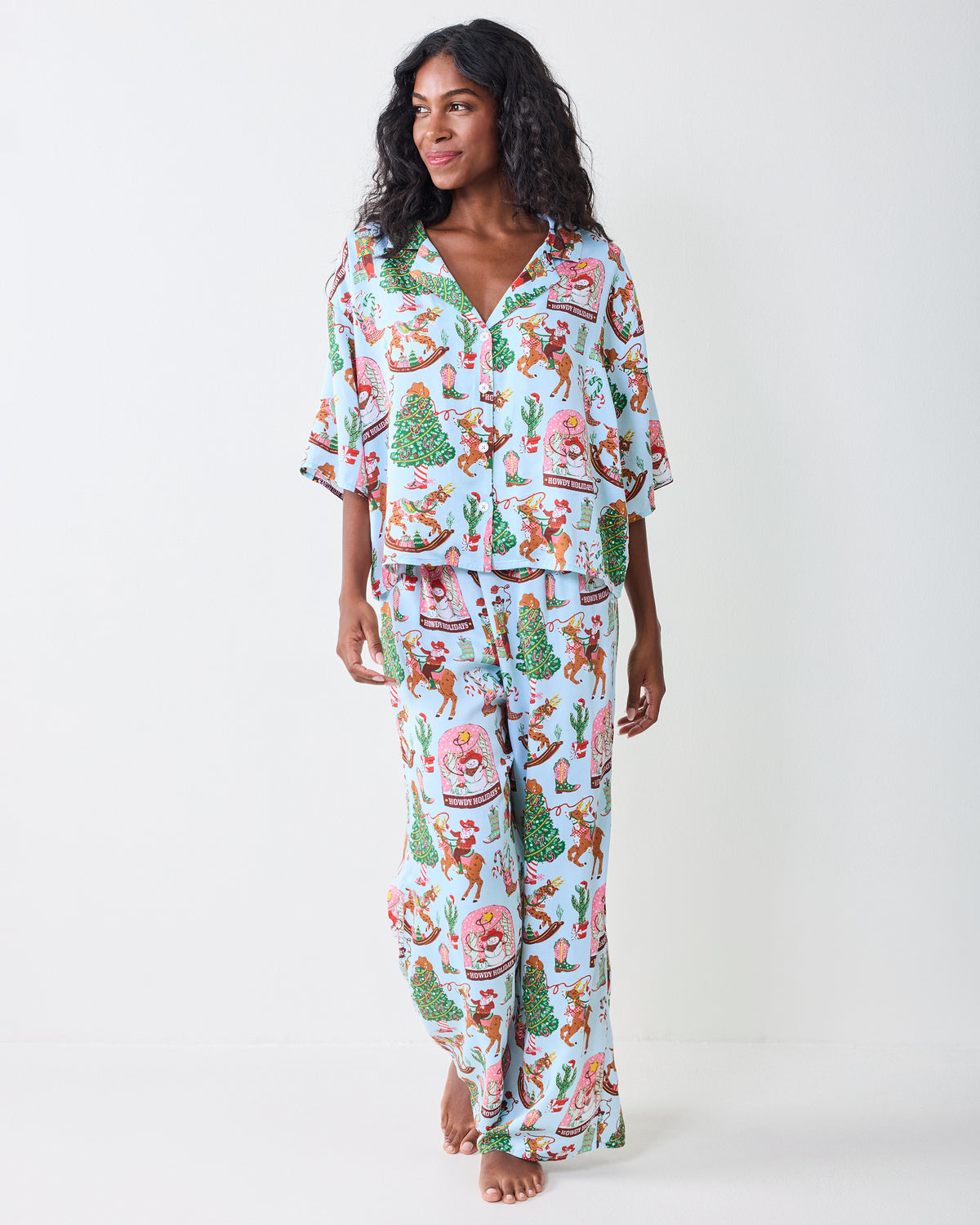 Full-length view of the pale blue Cowboy Christmas pajama set with a button-front top and wide-leg pants covered in holiday Western illustrations.