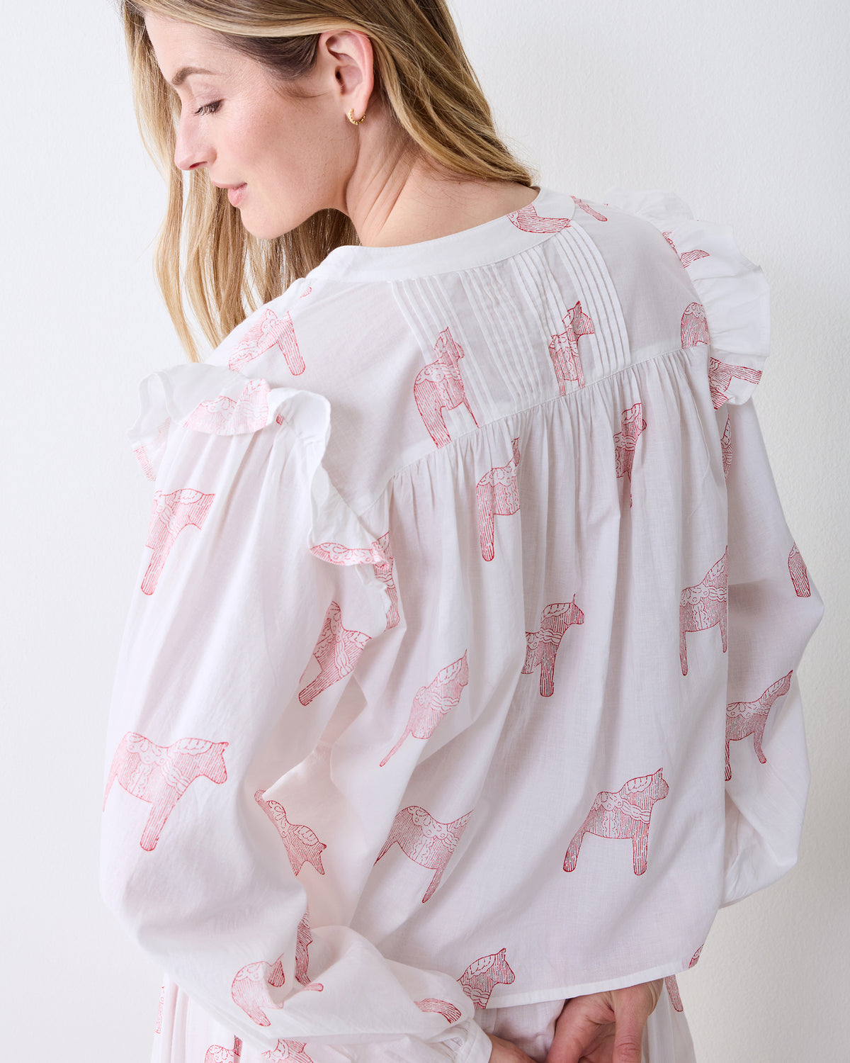 Back view of the Arctic Rose Dala Horse Millie Set top showing the gathered yoke, ruffled shoulders, long sleeves, and pink horse print.