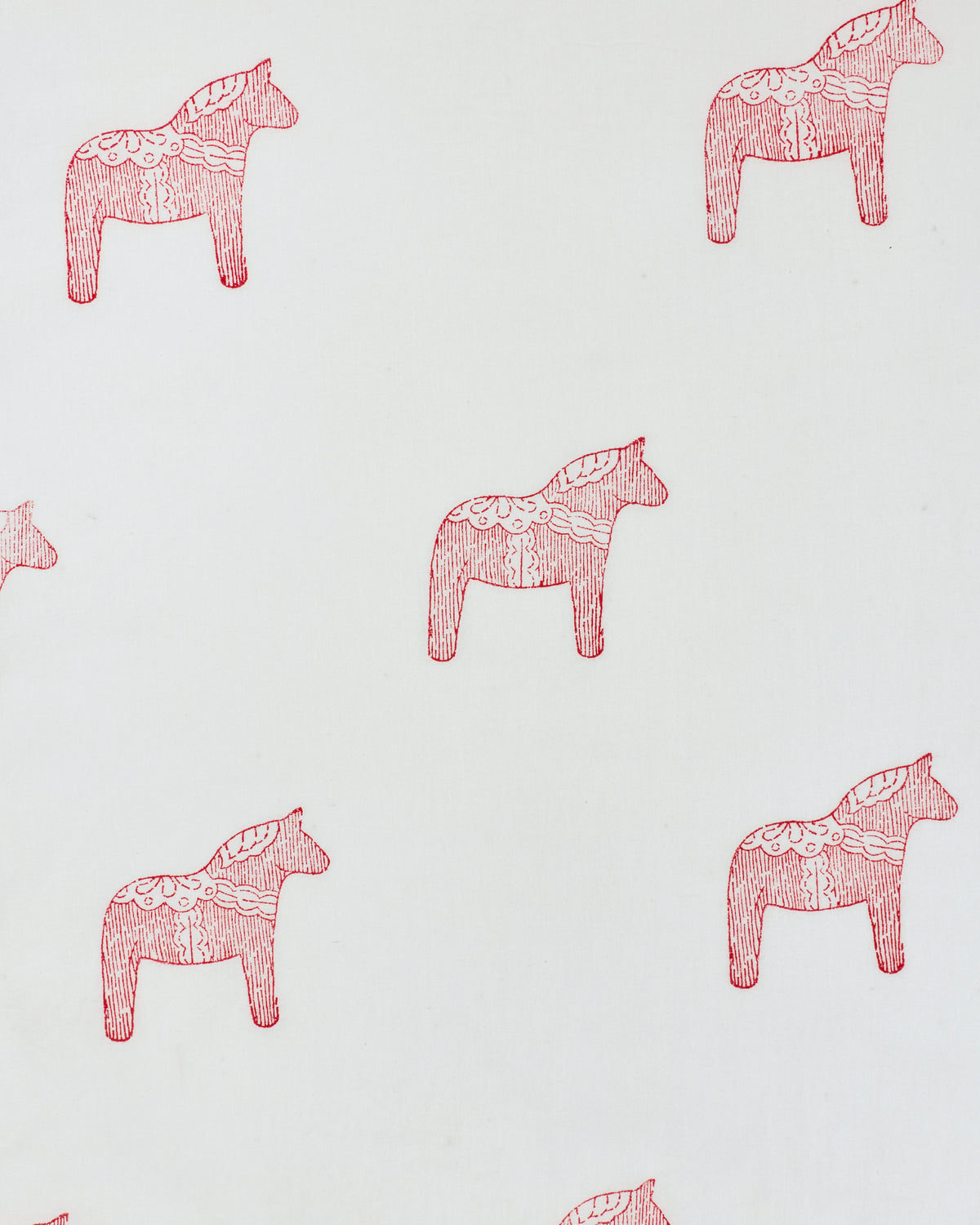 Close-up of a white fabric print with repeated pink decorative horse motifs.