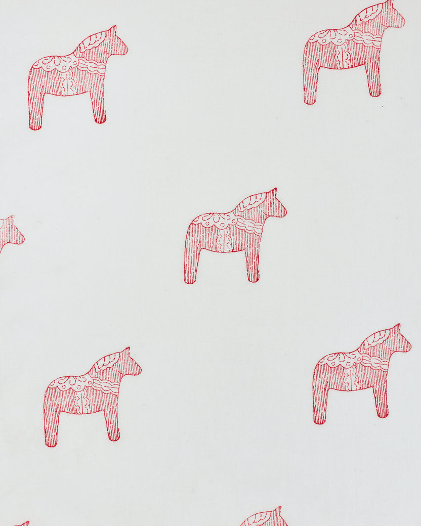Close-up of a white fabric print with repeated pink decorative horse motifs.