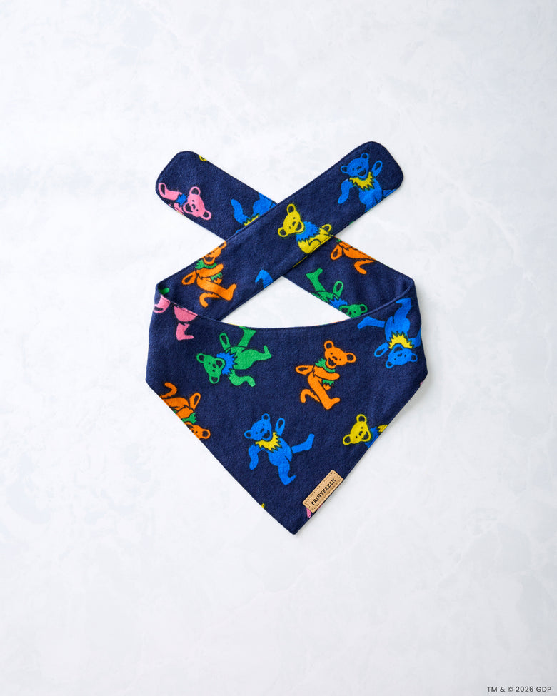 Navy Dancing Bears pet bandana laid flat at an angle, showing crossed tie straps and colorful bear figures.