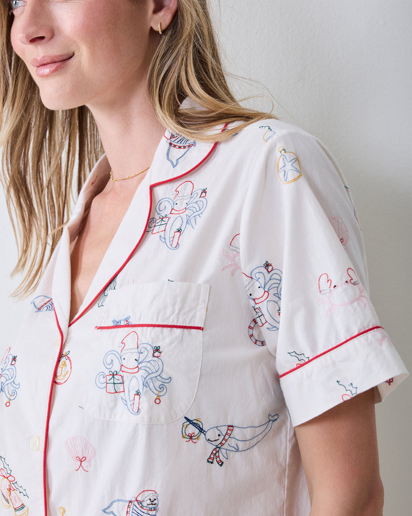 Close-up of the embroidered Yule Tides cloud Short PJ Set showing the collar, chest pocket, red piping, sleeve cuff, and stitched motifs.