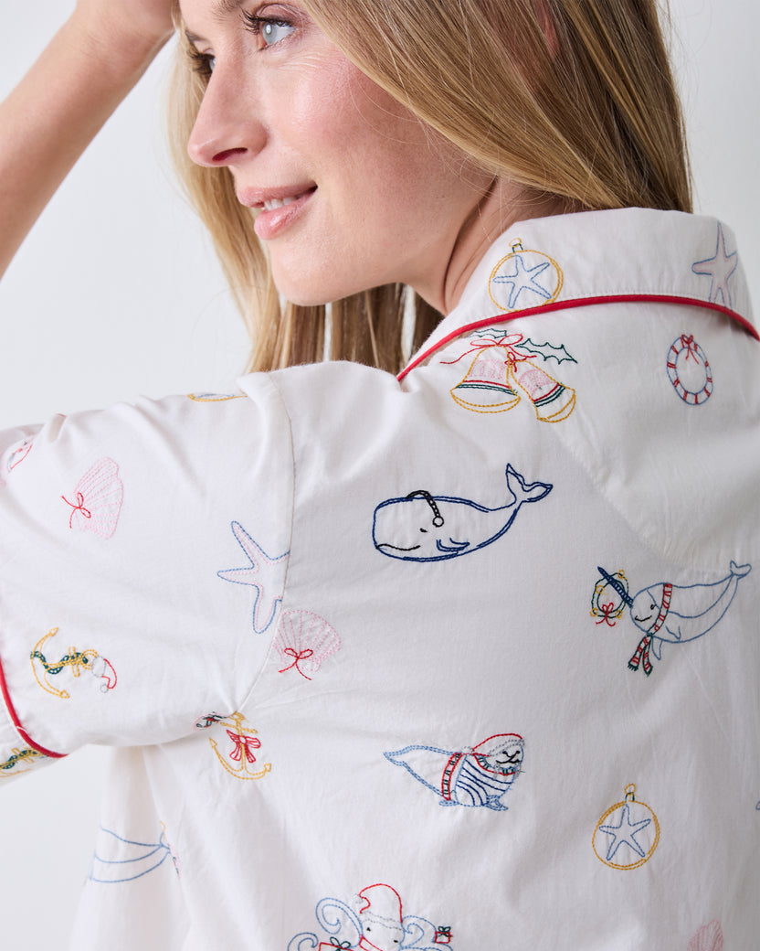 Close-up of the Cloud short pajama top showing embroidered whale, seal, starfish, bells, and other nautical and holiday motifs.
