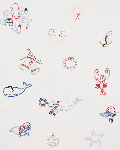Close-up of the embroidered Yule Tides cloud print with festive and nautical motifs, including whales, lobster, bells, ornaments, and sea creatures.