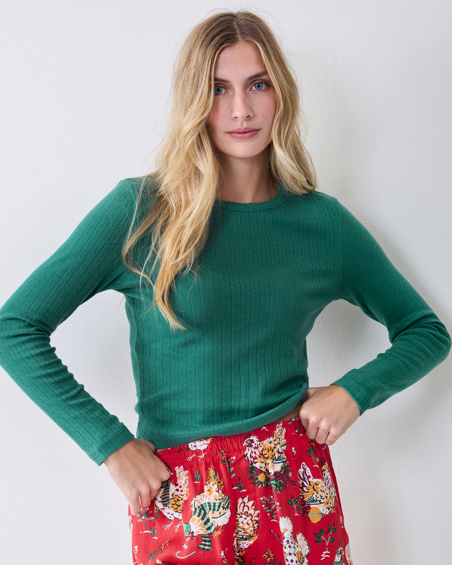 Front view of the evergreen long-sleeve pointelle top worn with red patterned pajama pants.