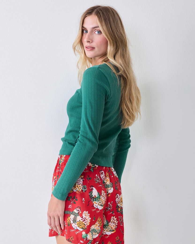 Three-quarter view of an evergreen long-sleeve pointelle top with a scalloped neckline and vertical eyelet pattern.