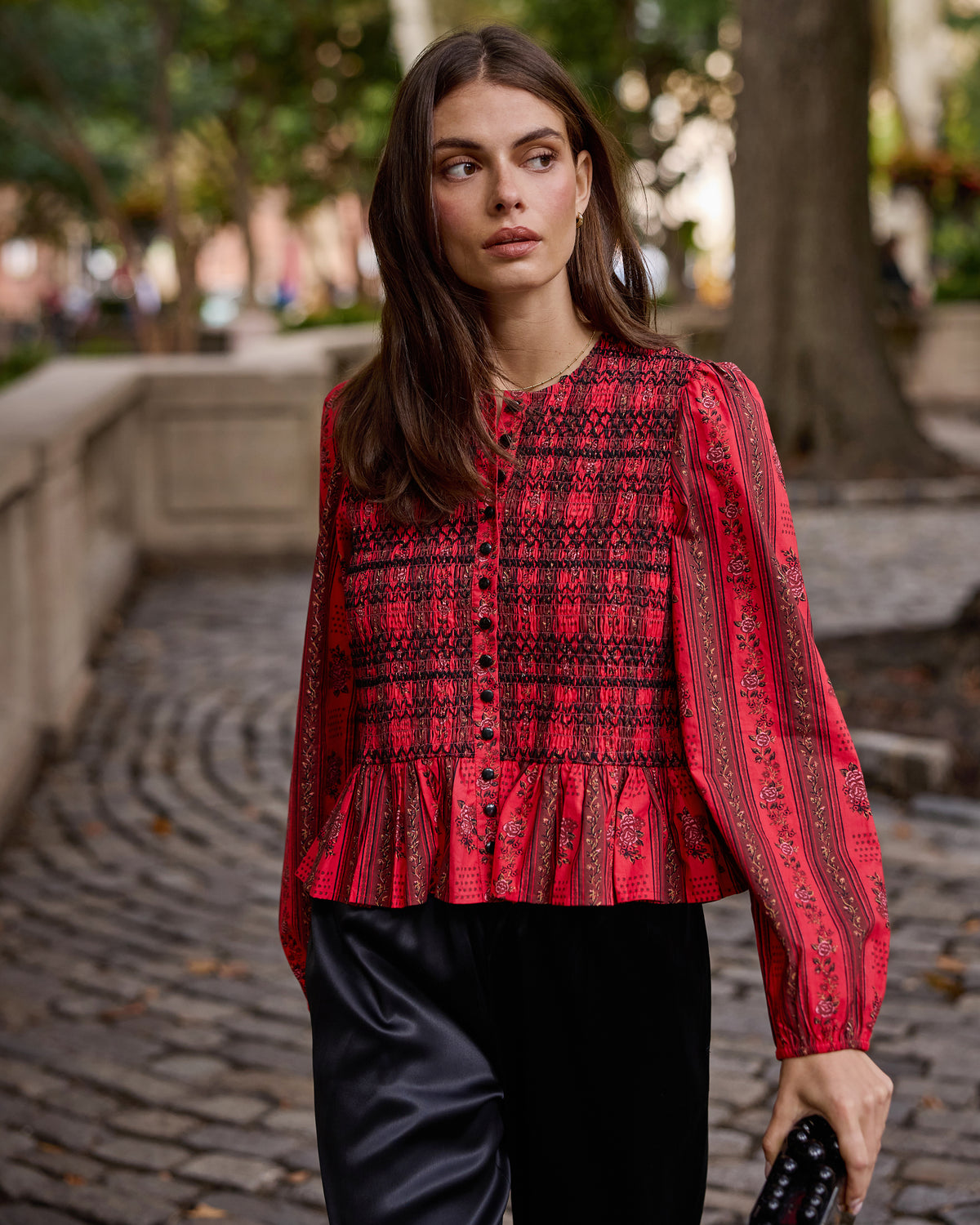 Front view of a person wearing the Heirloom Red Festive Roses Lavelle blouse, with a smocked bodice, button front, puffed sleeves, and peplum hem.