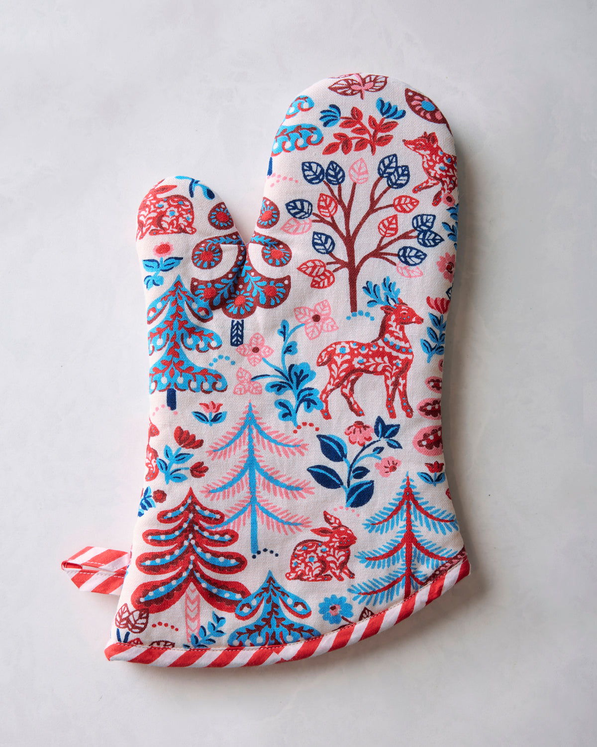 Reverse view of the cream oven mitt with red and blue woodland-pattern print, striped red trim, and hanging loop.