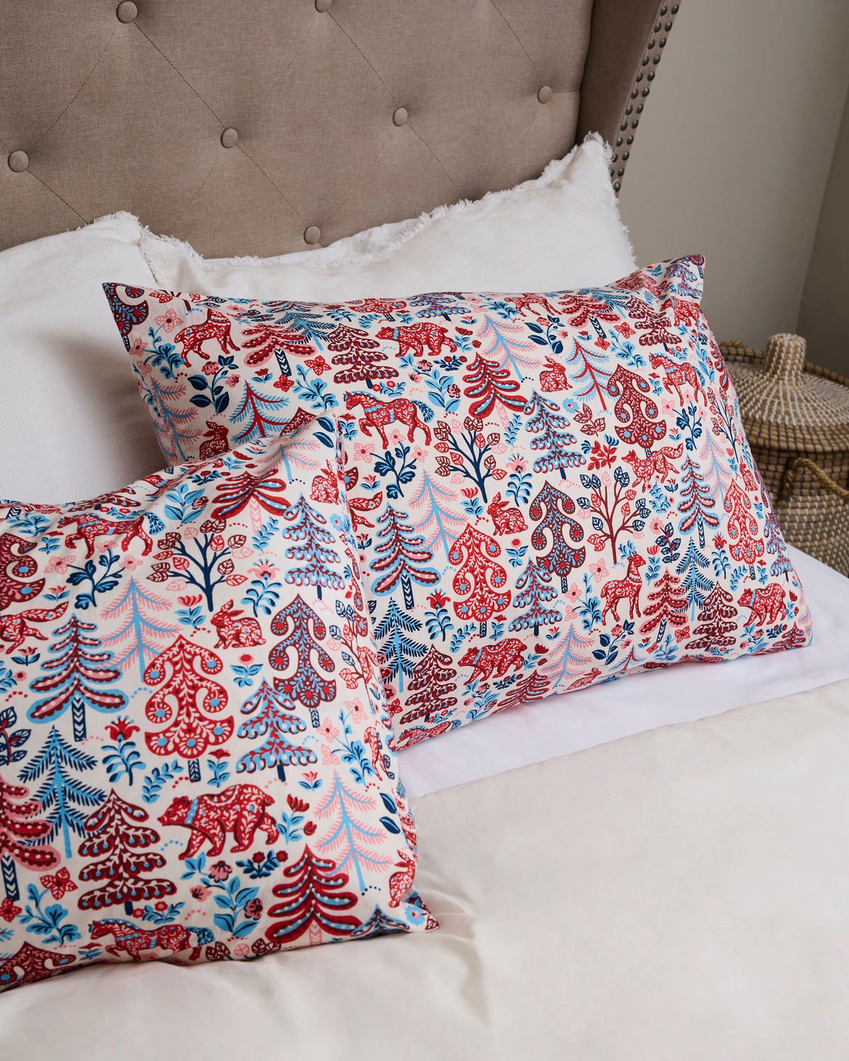 Two Folklore Forest patterned pillowcases arranged on a bed, with one in front of the other.