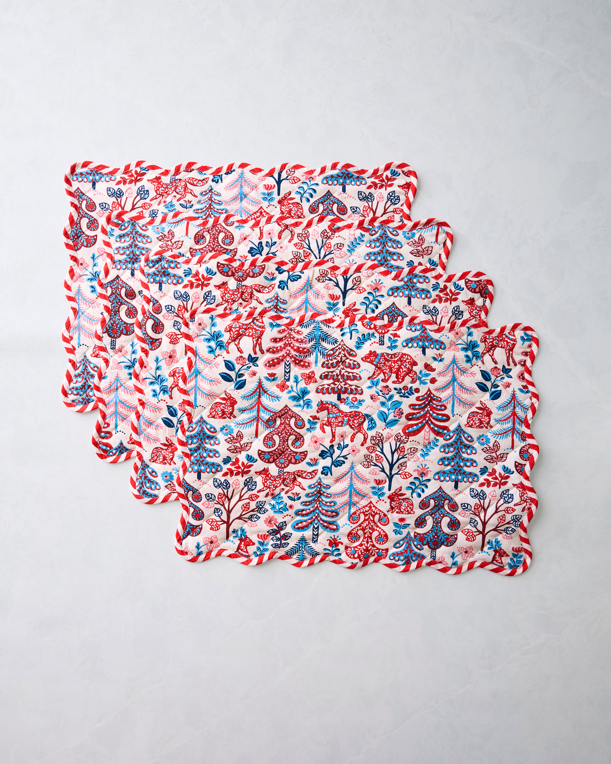 Four Folklore Forest placemats stacked in an overlapping horizontal arrangement.