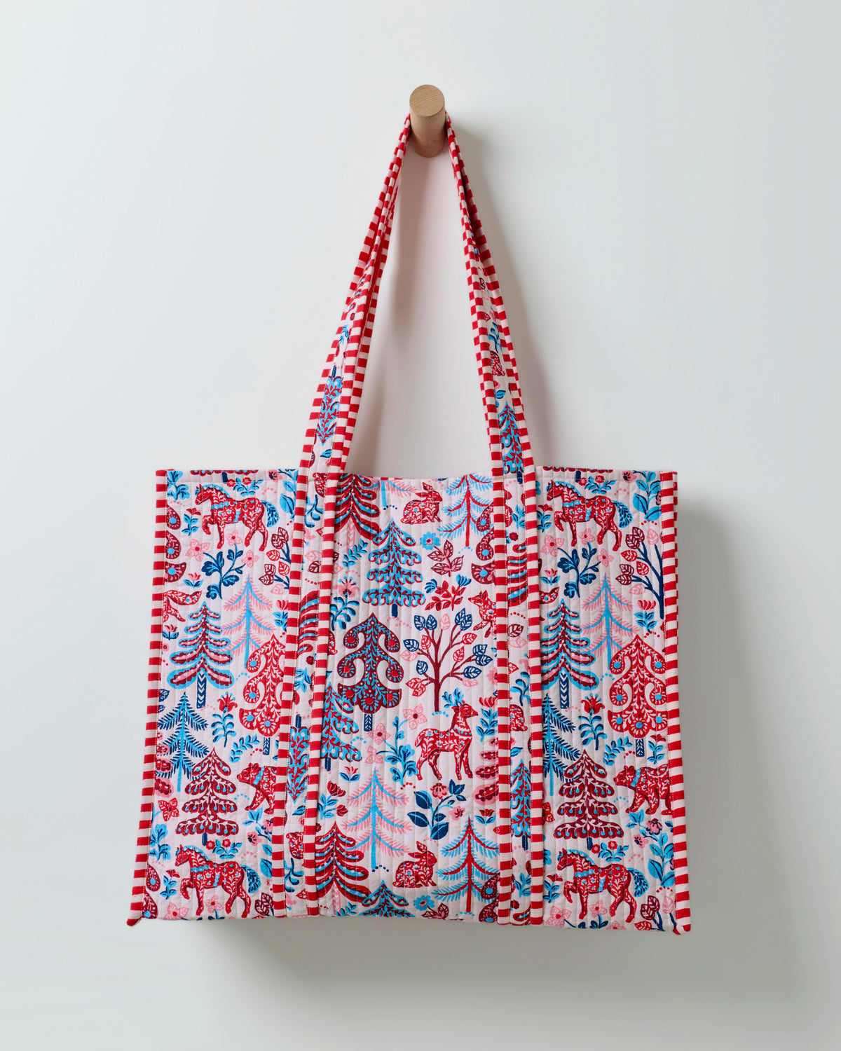 Front view of a cream patterned tote bag with two long handles and striped trim.