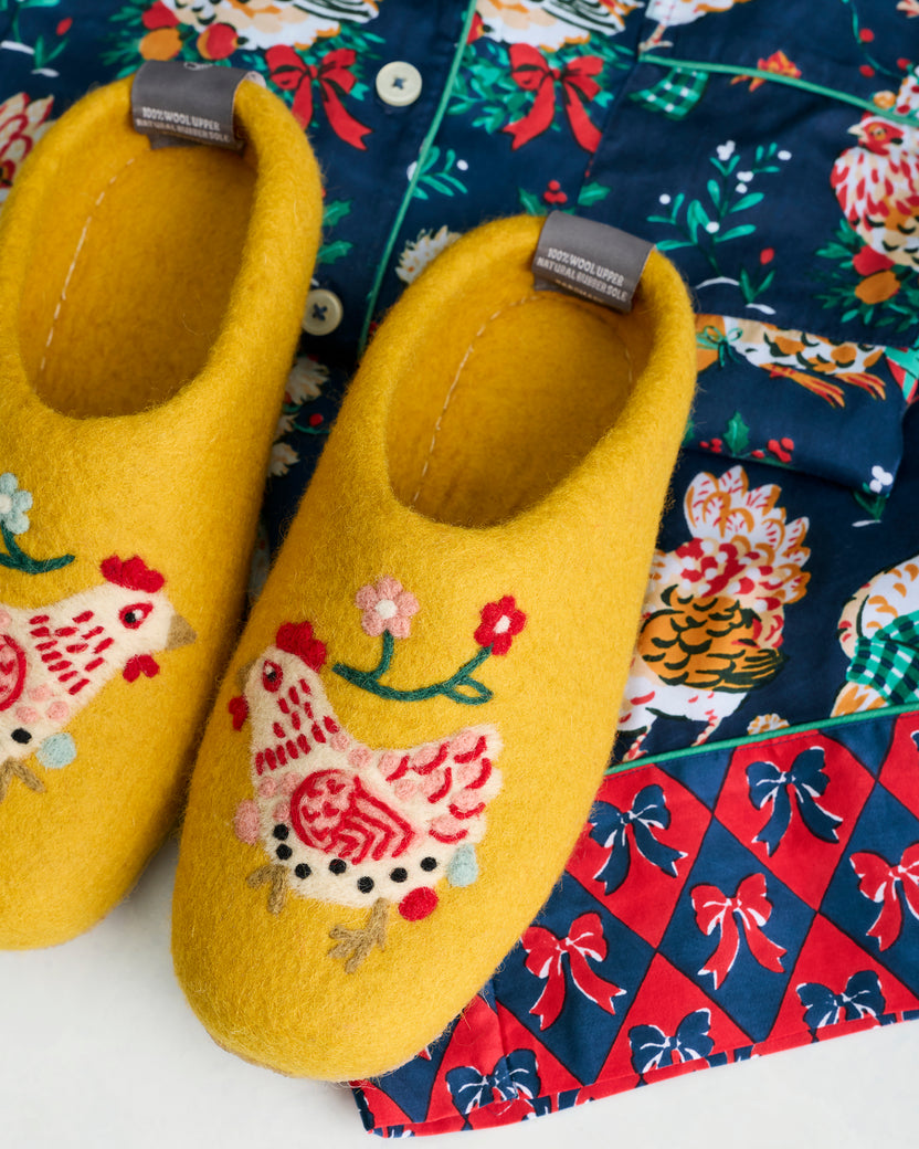 Close-up of yellow Holiday Hens slippers showing the felted hen motifs and stitched insoles.