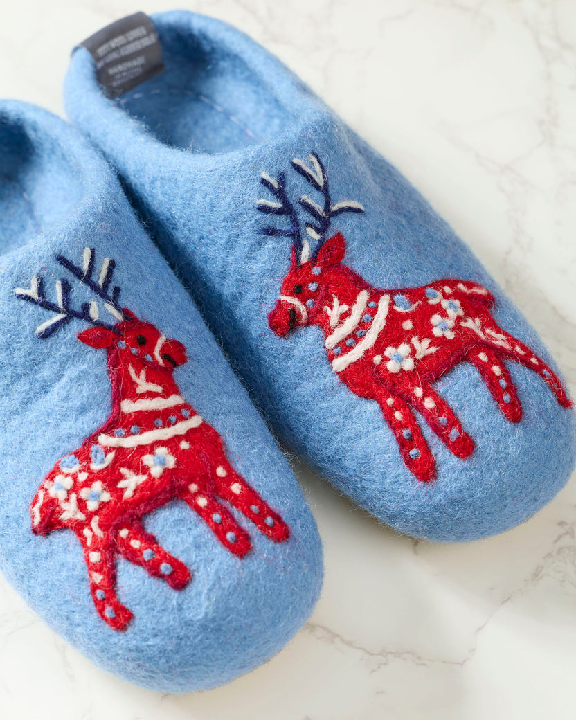Close-up of light blue slippers with red reindeer decorations.