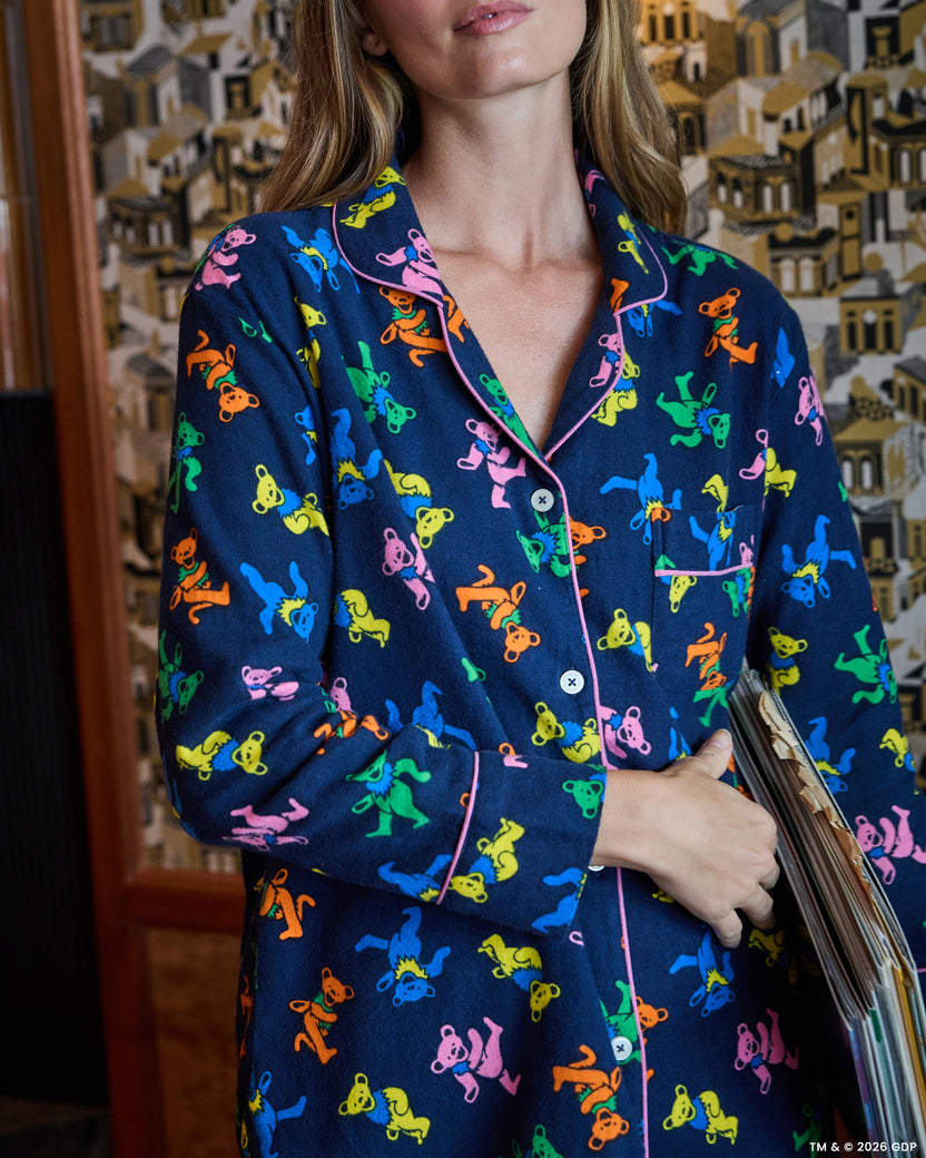 Close view of the navy long pajama top with a multicolor dancing-bear print, pink piping, buttons, collar, and chest pocket.