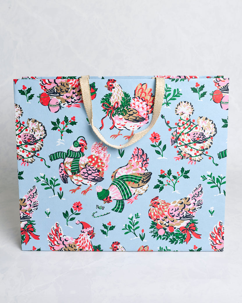 Front view of the Holiday Hens pale blue handmade gift bag with decorated hens, holly branches, berries, and tan handles.