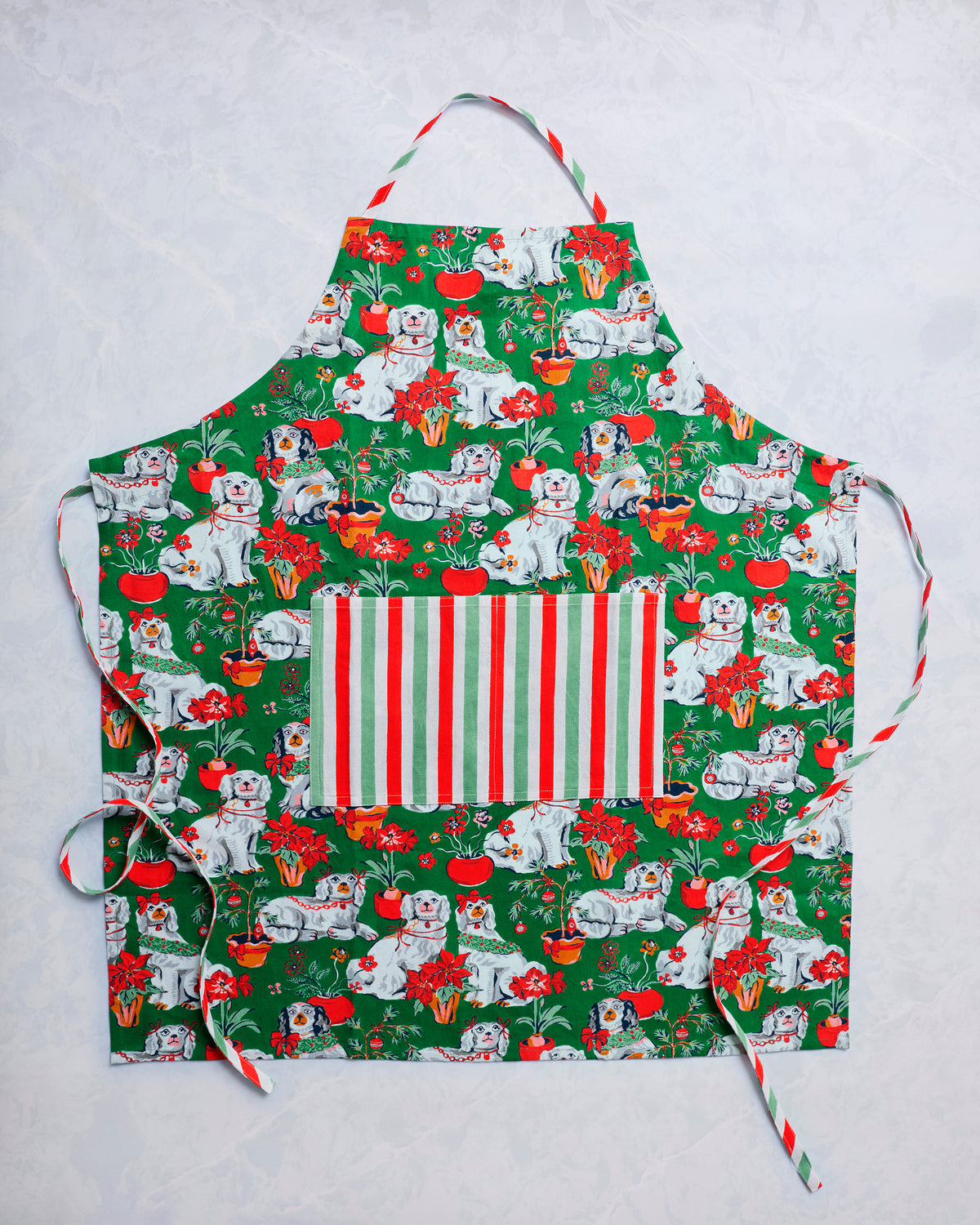 Green Good Dog Christmas apron with an all-over dog and holiday plant print, striped front pocket, and neck strap