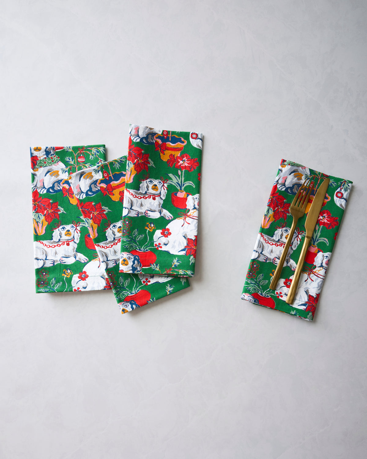 Four green Good Dog Christmas dinner napkins displayed together, with one folded around a fork and knife.