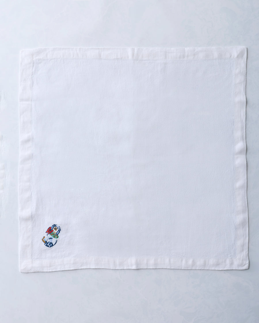 Single white dinner napkin with a small embroidered dog figurine near one corner