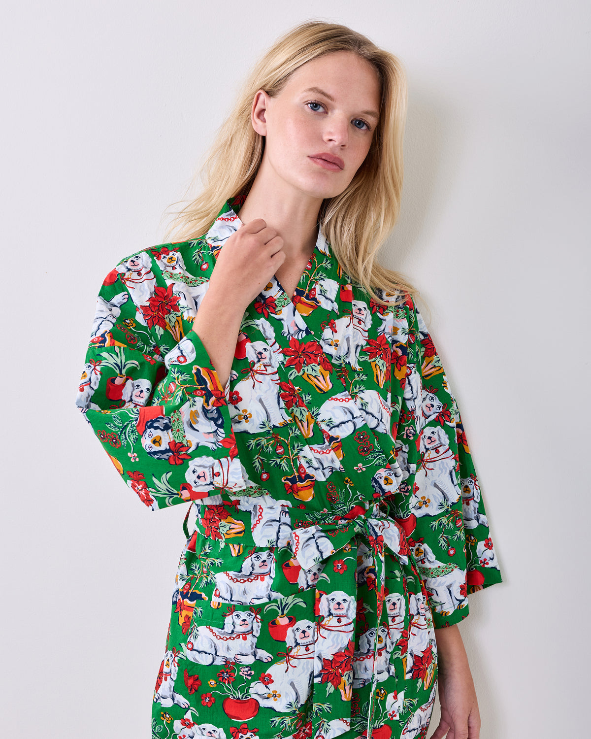 Close-up of the green Good Dog Christmas robe showing its collar, waist belt, long sleeves, and dog-and-poinsettia holiday print.