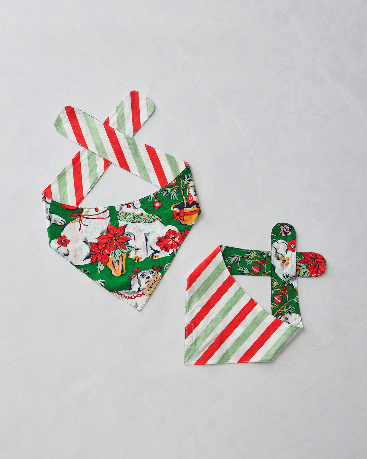 Two Good Dog Christmas pet bandanas displayed flat, showing the printed dog pattern and striped reverse side.