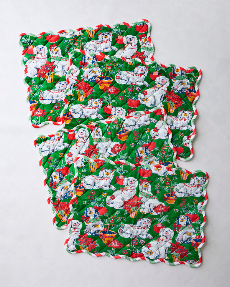 Four green Good Dog Christmas placemats arranged separately to show their scalloped edges and dog-and-holiday print.