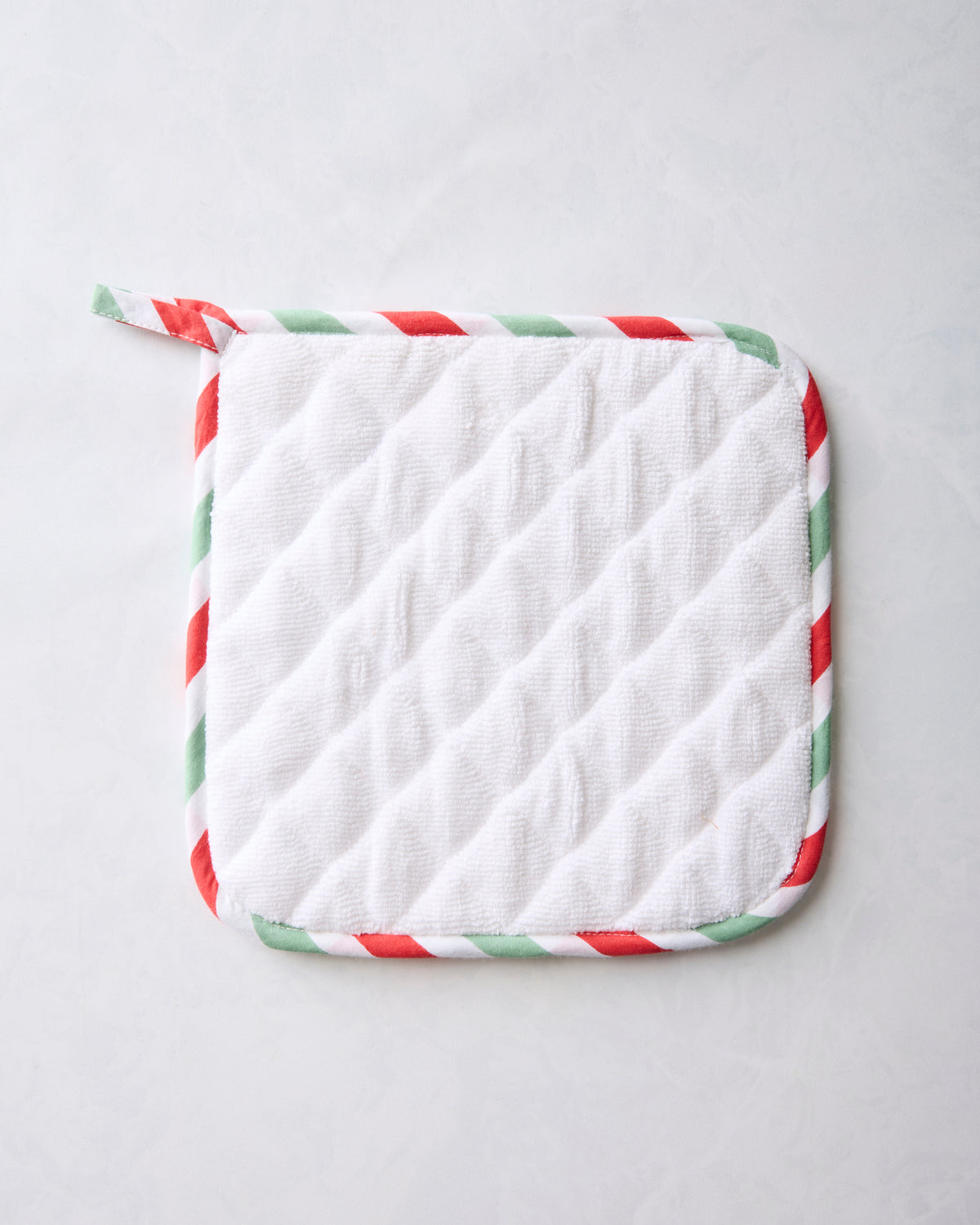 Back of the Good Dog Christmas pot holder with a white quilted surface and red-and-green striped trim