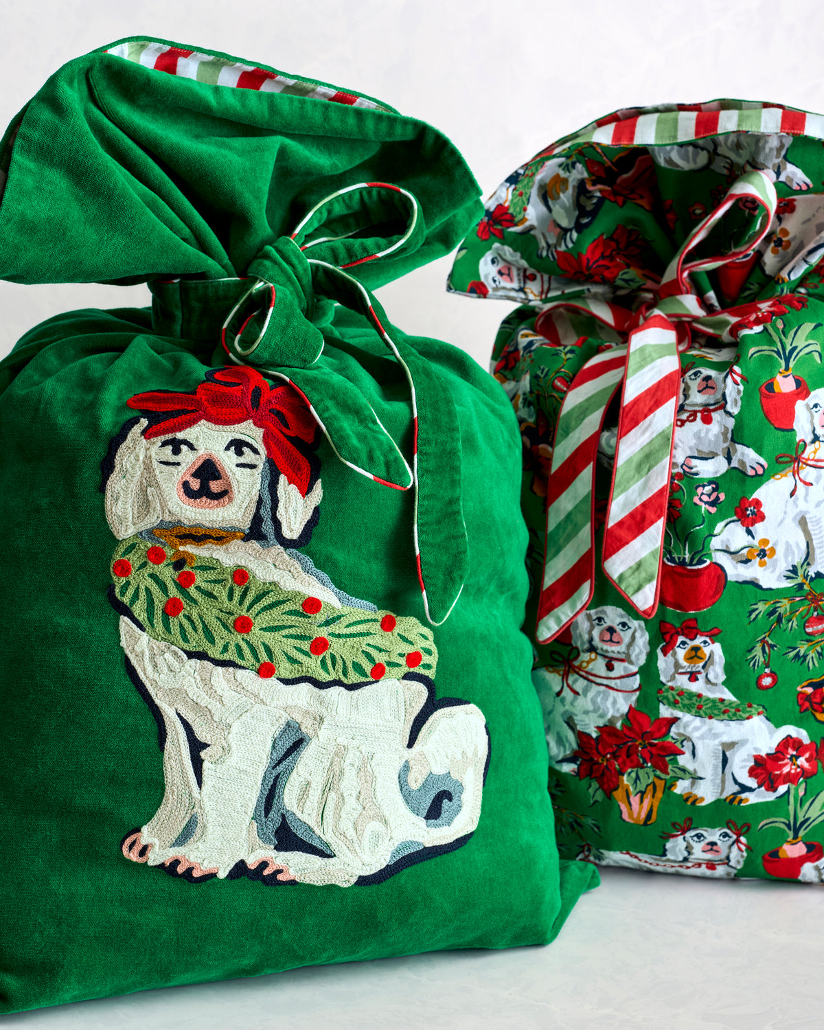 Two Christmas gift sacks: one green sack with a dog design and one coordinating sack with a festive dog print and striped ties.