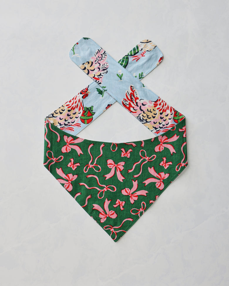 Pet bandana shown flat with a green side featuring a pink bow print and pale blue patterned ties.