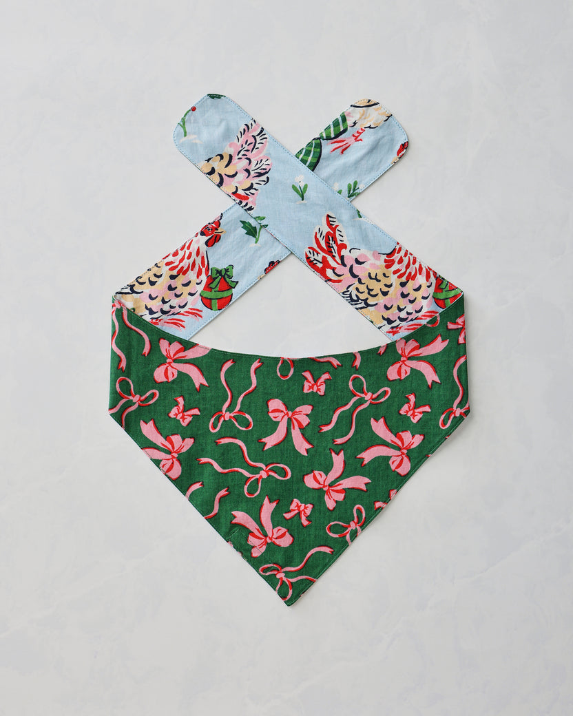 Pet bandana shown flat with a green side featuring a pink bow print and pale blue patterned ties.
