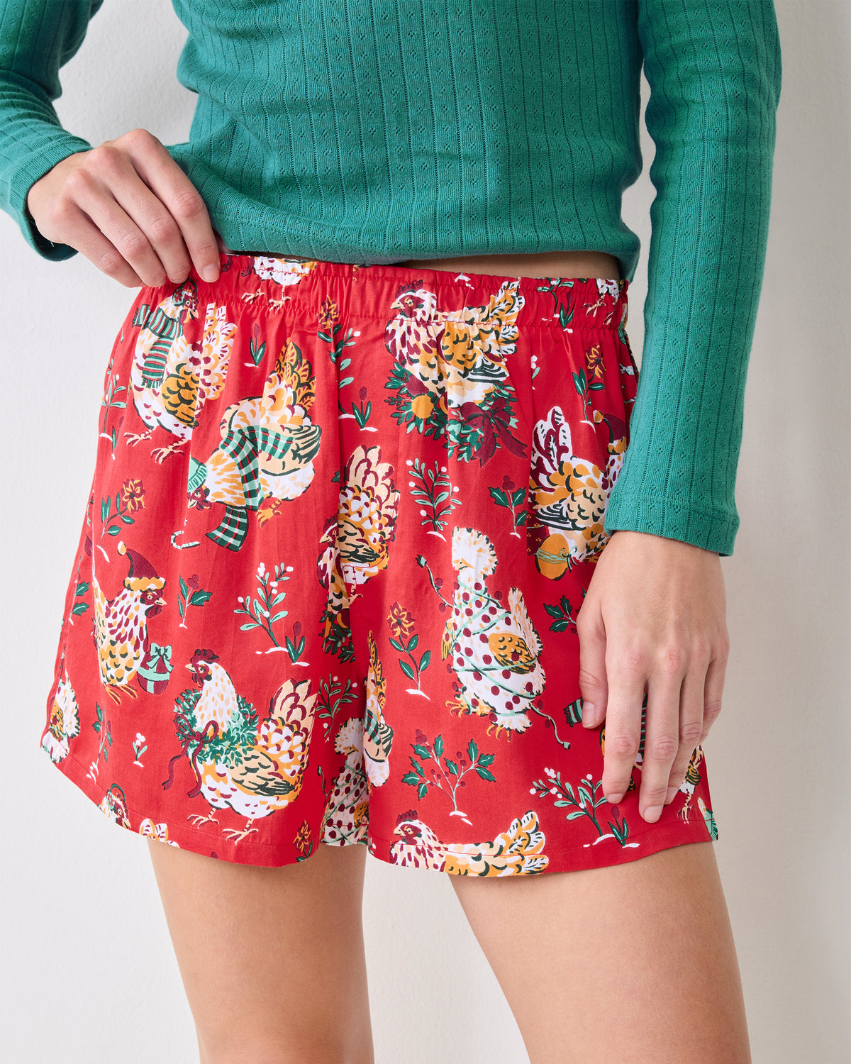 Close view of the red Holiday Hens boxer shorts showing the elastic waistband, short legs, and chicken-and-foliage print.