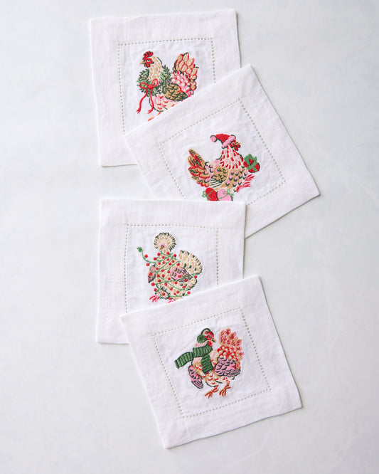 Four embroidered chicken cocktail napkins overlapping in a diagonal arrangement