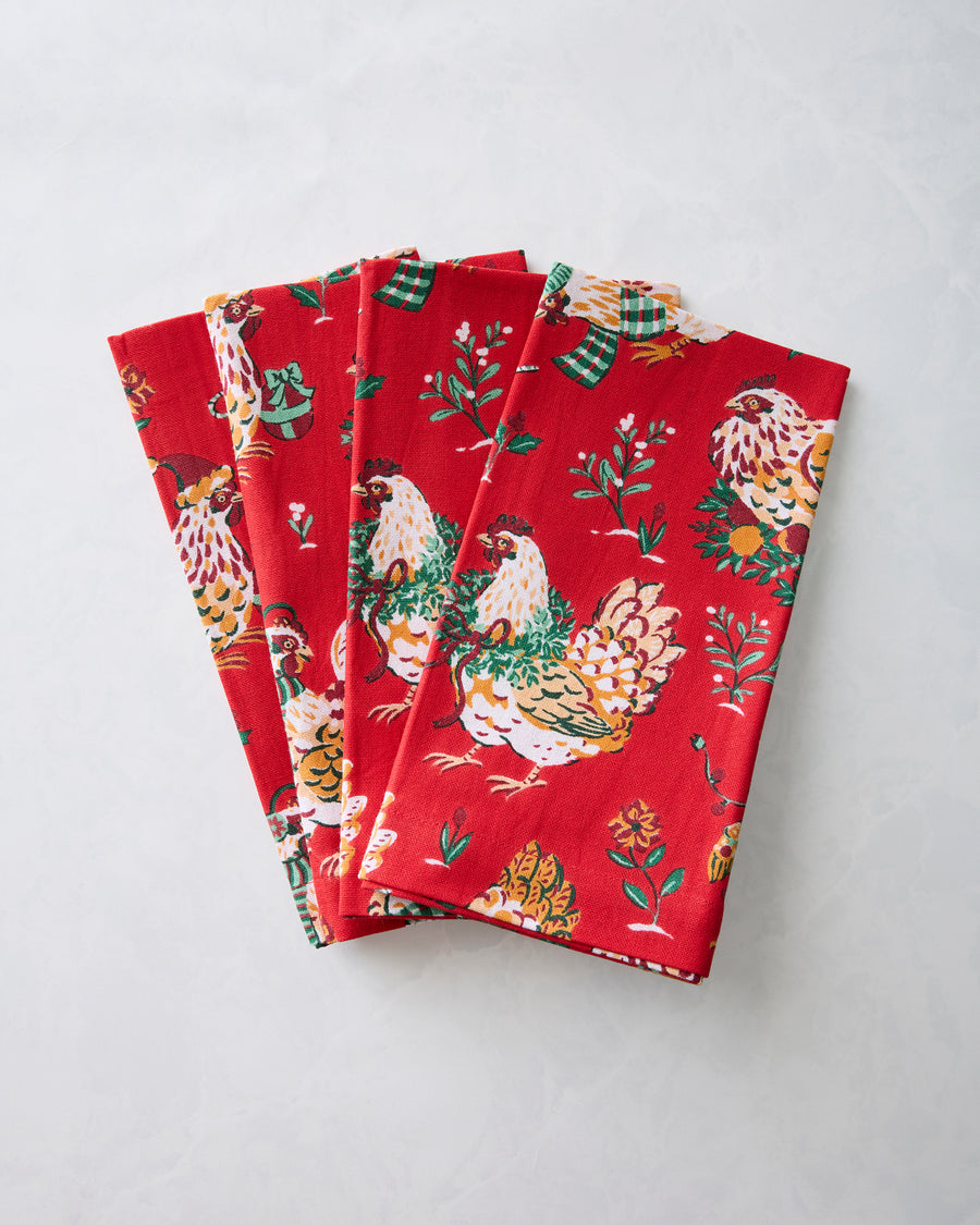 Folded red dinner napkins with a holiday hen and floral print.