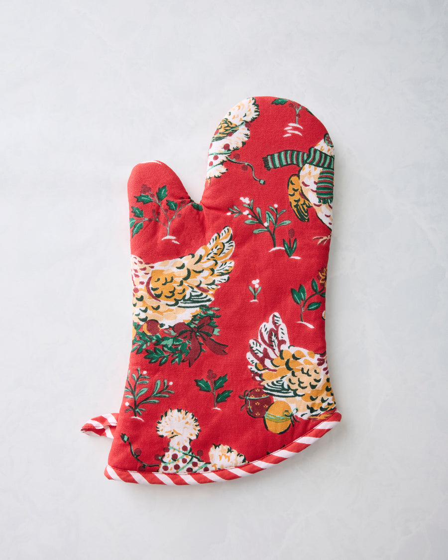 Reverse view of a red oven mitt with chicken, greenery, and holiday accessory motifs, finished with candy-cane striped trim.