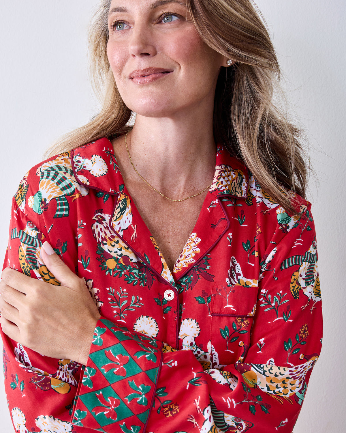 Close-up of a red chicken-print button-front pajama top with a notched collar, chest pocket, and long sleeves.