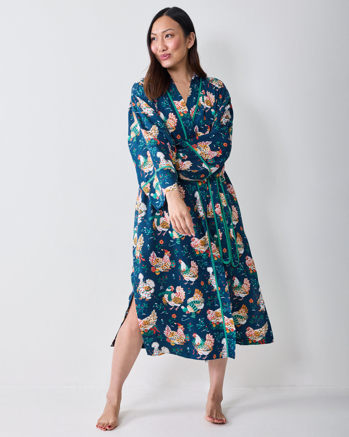 Full-length view of a model wearing the Holiday Hens wrap robe with a contrasting belt and chicken print.